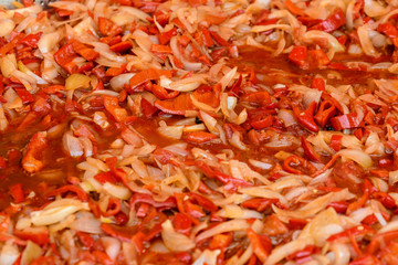 Clouse up of many fresh cut red peppers and onions boiling for a vegetable soup