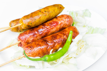 Pork sausage in a white dish with green peppers.