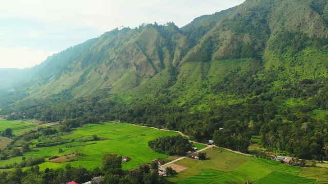 Aerial: lake Toba and Samosir Island view from above Sumatra Indonesia. Huge volcanic caldera covered by water, traditional Batak villages, green rice paddies, equatorial forest.