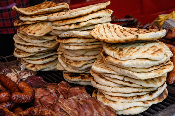 Home made pita bread displayed with different types of meat, for sale at a street food market