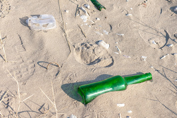 green glass bottle left by a man on the sand beach.