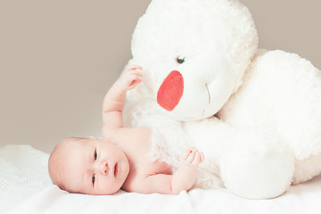 pretty newborn baby girl with a big soft toy lying on the blanket.