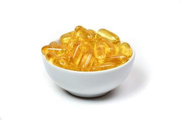 Close up of gold fish oil capsules in cup isolated on white background. Omega 3 with Vitamin E. Salmon fish capsules. Supplementary food background view.