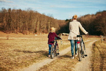Fototapeta premium Mother and daughter with bicycles on countryside.