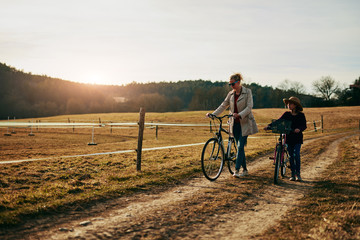 Fototapeta premium Mother and daughter with bicycles on countryside.