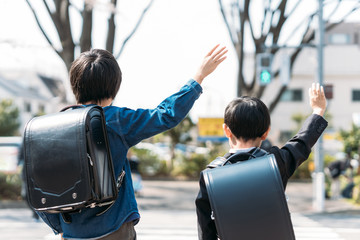 交差点で手を挙げる小学校高学年生と1年生