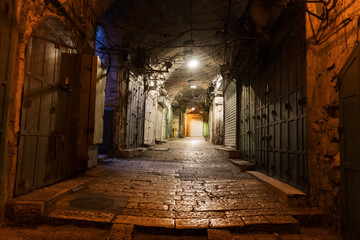 Narrow cobbled street in old medieval town with illuminated houses and pavement. Night shot of side passage in some ancient castle. Closed doors, stone paving and hanging lights in the street. © diy13