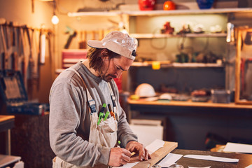 Male carpenter working on old wood in a retro vintage workshop.