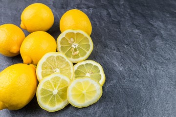 Ganze Zitronen und in Scheiben geschnittene auf einer Küchenarbeitsplatte