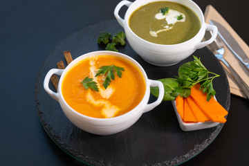 Two bowls of pumpkin and broccoli soup with cream