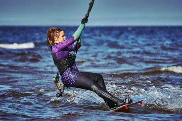 A female kiter slides on the surface of the water. Splashes of water fly apart. Close-up.
