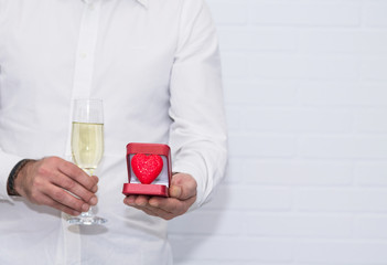 man with glass of champagne and box with red heart, greeting card