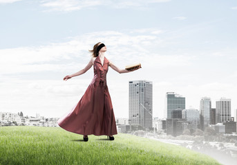 Obraz premium Girl against cloudy sky with opened book in palm as idea for knowledge