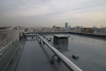 雨の後の屋上のウレタン塗膜防水と都心の眺め