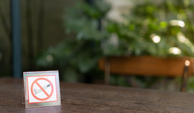 No smoking sign position on the left  of the wood table in dark blur background