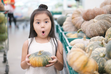Asian child cute or kid girl open mouth wow and holding pumpkin vegetable or fruit for buy or sale...