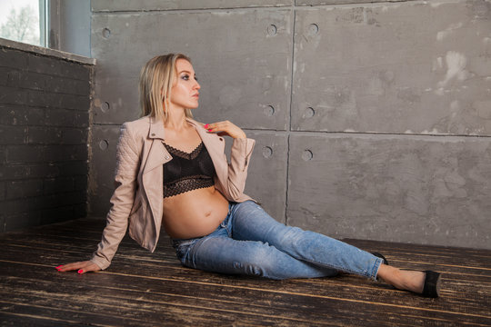 Modern stylish pregnant blonde in jeans and top. Bold image of motherhood.