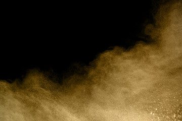 Golden powder explosion on black background. Freeze motion.