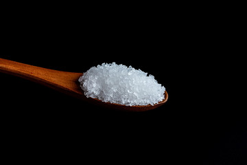 a spoonful of coarse sea salt on a black background