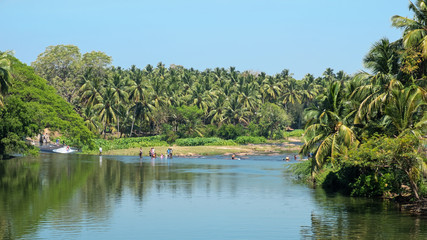 Scene on the river Noyyal, in the Tiruppur district of Tamil Nadu in southern India, with local people bathing and washing clothing at a natural ford