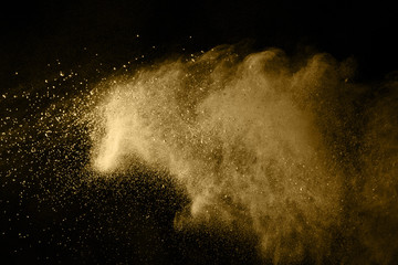 Golden powder explosion on black background. Freeze motion.
