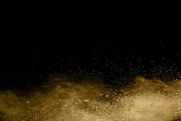Golden powder explosion on black background. Freeze motion.