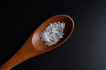 a spoonful of coarse sea salt on a black background