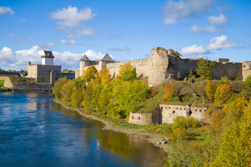 Fototapeta na wymiar View of the Herman castle and Ivangorod fortress in the golden autumn. Border of Russia and Estonia