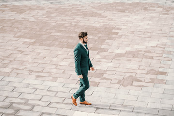 Successful Caucasian bearded businessman in formal wear walking on the rooftop. Create a vision that makes you wanna jump out of bed in the morning.