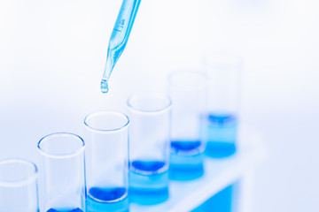 Someone dropping blue liquid in test tubes..