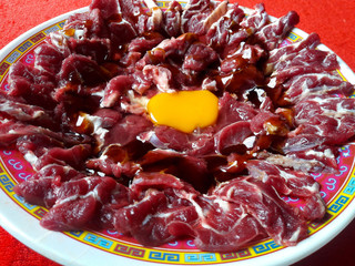 Yellow eggs placed on the middle, fresh red sliced ​​thin meat and served on a red table