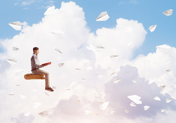 Handsome man student reading book and paper planes flying around