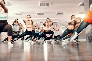 Fototapeta premium Group of Caucasian cheerful women standing in gym and doing stretching exercises. For good thing sin life takes time and persistence.