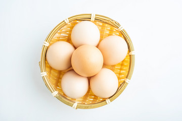 a bamboo basket of raw eggs on a white background