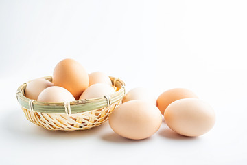 a bamboo basket of raw eggs on a white background