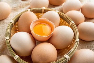 Raw bamboo basket with raw eggs on burlap background