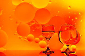transparent glasses with water and oily drops on colorful background 