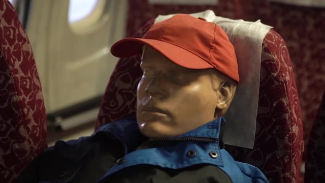 man`s manikin sitting in a chair inside a airplane