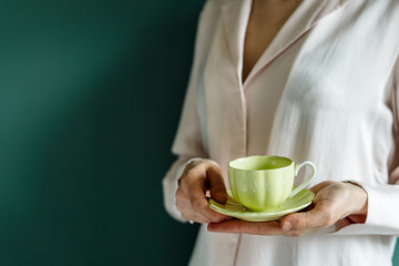 Girls holding up a yellow cup on a uniform background in a cozy lifestyle image with copy space.