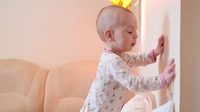 Little boy turns the light on and off. Ten month old baby boy stands on the sofa and plays with light. 4K UHD