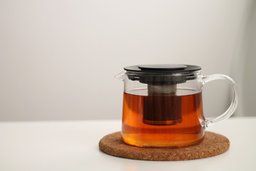 transparent teapot with tea on light background