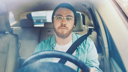 Portrait of Stylish Young Man Drives Car through big Sunny City. Shot Made From the Front Windshield.