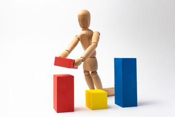 Wooden man builds a diagram of colored blocks on a white background.