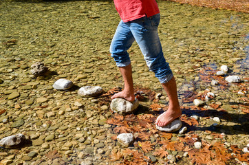 passing the river on the stonen young man feet river voidomatis zagoria ioannina  greece