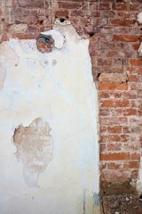 background of cracked plaster covered shabby old brick wall, vertical rough abstract surface texture photo