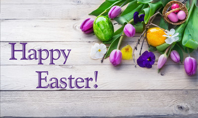 Happy Easter, colorful easter eggs and spring flowers on bright wood