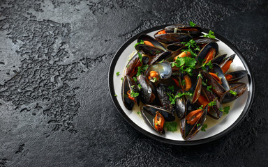 Mussels with white wine, garlic, lemon and herbs in a plate, rustick background. Seafood.