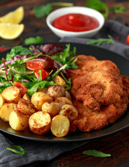 Homemade breaded pork schnitzel with roast potato and vegetables