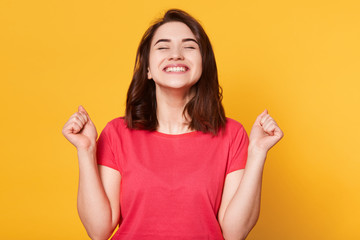 Image of attractive woman with dark straight hair, stands with closed eyes, clenches fists and...