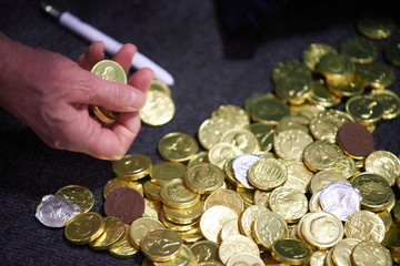 Person z&auml;hlt auf dem Boden liegende M&uuml;nzen aus Schokolade